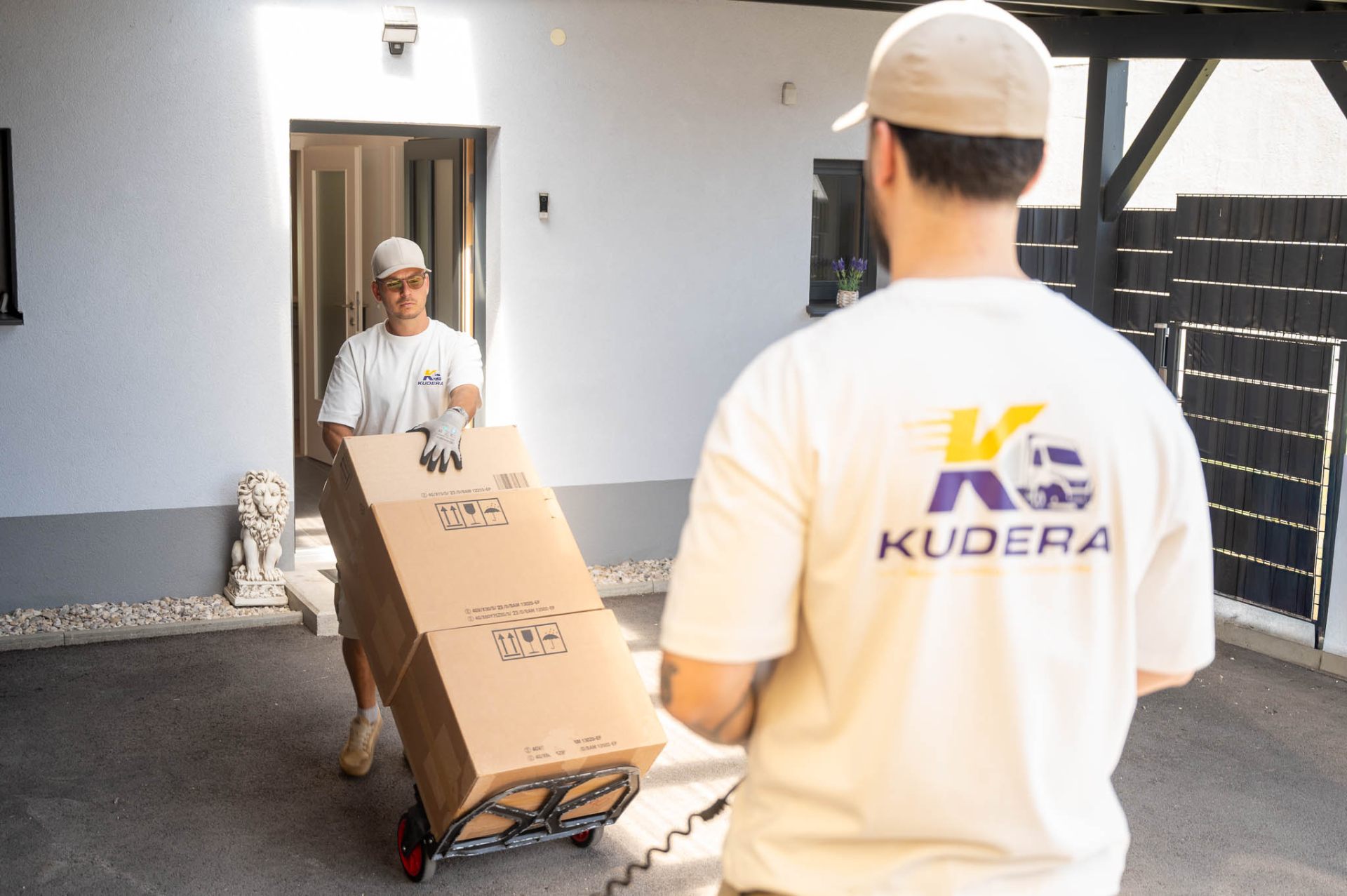 Kudera Team übergibt Kartons mit Sackrolle vor dem Haus